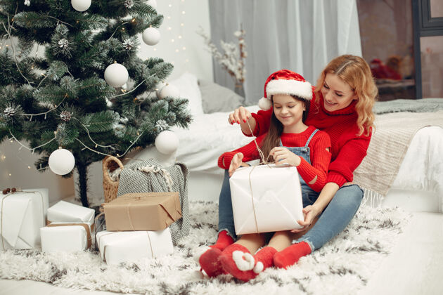 礼物人们在为圣诞节做准备母亲在和女儿玩耍一家人在节日的房间里休息孩子穿着红色毛衣坐面纱圣诞