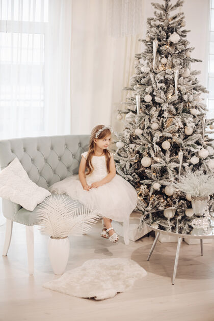 传统年轻的白衣白人女孩在圣诞气氛中对着镜头摆姿势圣诞树孩子新的