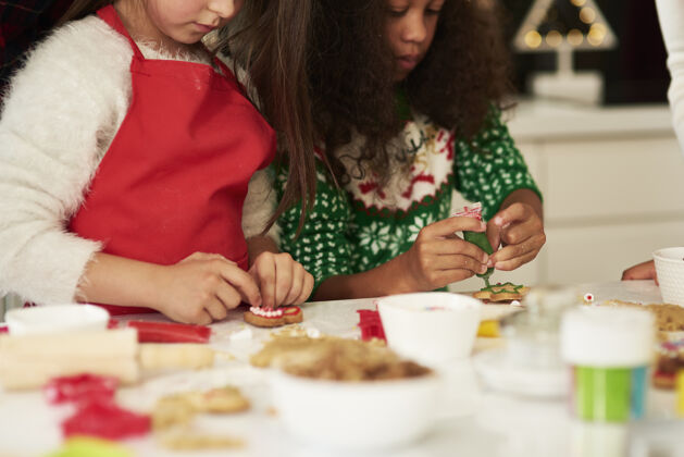 桌子两个女孩在装饰圣诞饼干毛衣蛋糕人