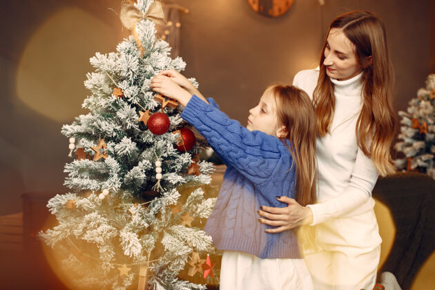 毛衣人们在为圣诞节做准备母亲在和女儿玩耍一家人在节日的房间里休息孩子穿着蓝色毛衣女性母亲给