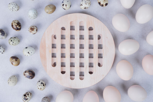 俯视图白色表面的有机鹌鹑蛋和鸡蛋汤匙鹌鹑有机