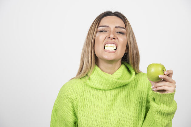 吃穿着绿色t恤的年轻女子正在吃苹果食物维生素水果