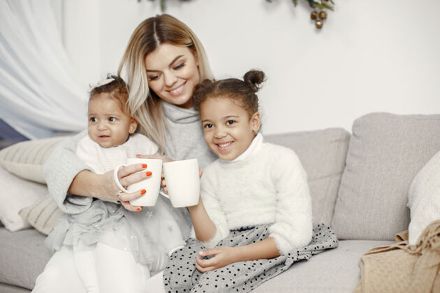 毛衣人们在为圣诞节做准备母亲在和女儿们玩耍一家人在节日的房间里休息孩子穿着毛衣女孩国际闪亮