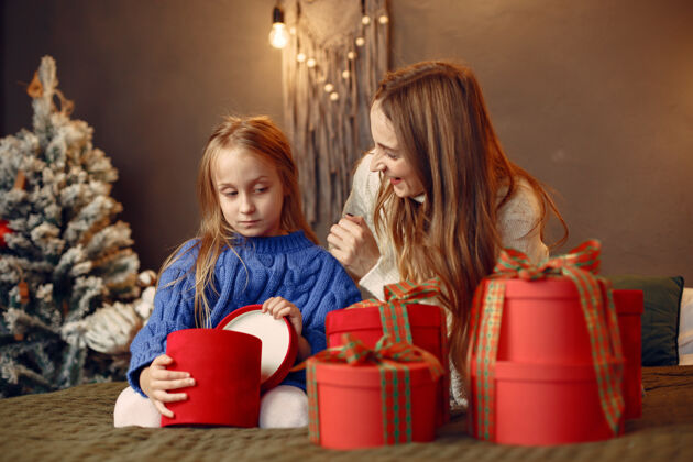 装饰人们在为圣诞节做准备母亲在和女儿玩耍一家人在节日的房间里休息孩子穿着蓝色毛衣杉木红色人