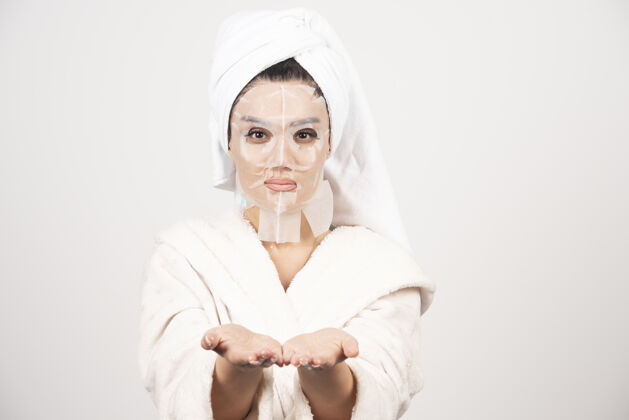 美丽穿着浴衣和带面罩的毛巾的女人面膜美容水疗