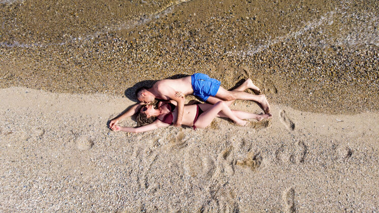 乐趣一对情侣拥抱着躺在爱琴海的海滩上 看着对方 泳衣 海浪到达他们身边 希腊 阿斯普罗瓦塔天空女性人际关系