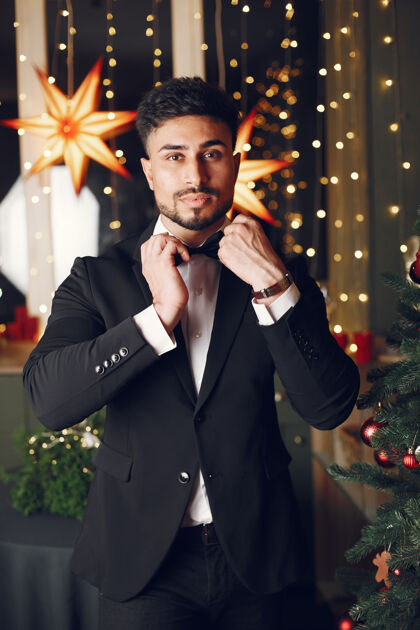 新年圣诞树附近的帅哥穿着黑色西装的绅士庆祝人除夕夜