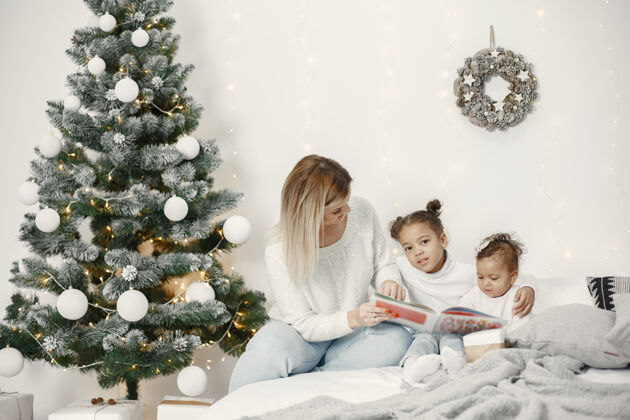 女儿人们在为圣诞节做准备母亲在和女儿们玩耍一家人在节日的房间里休息孩子穿着毛衣花环传统亮光