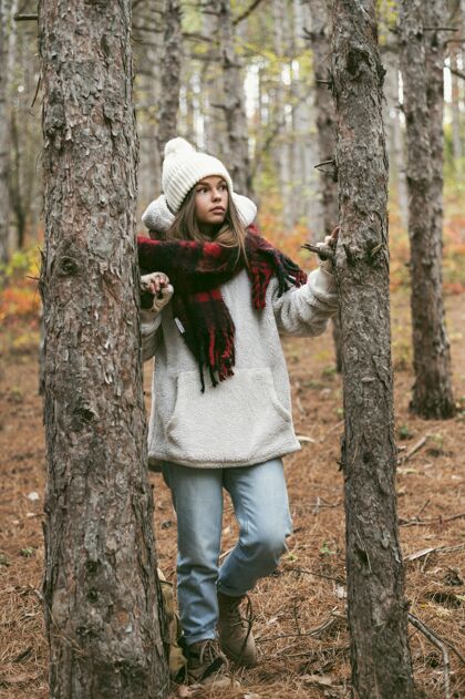 冬天穿冬衣的年轻女子站在树旁季节户外宁静