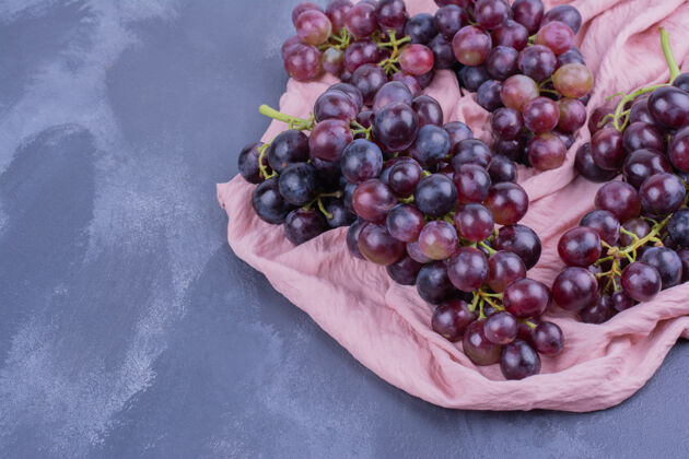 品质红葡萄串在一块粉红色的毛巾上极简产品蔬菜