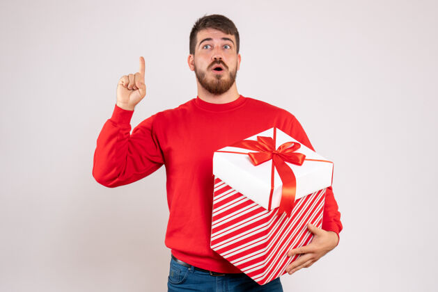 美丽前视图中的年轻人在红衫举行圣诞礼物在一个白色的墙壁框盒子人男性