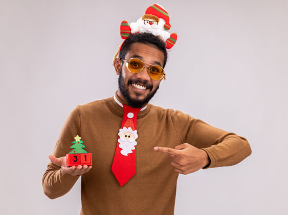 棕色快乐的非洲裔美国人穿棕色毛衣和圣诞老人圈拿着新年美国