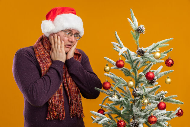 脸戴眼镜戴圣诞老人帽脖子上围着围巾的关心的成年人站着羽绒服眼镜