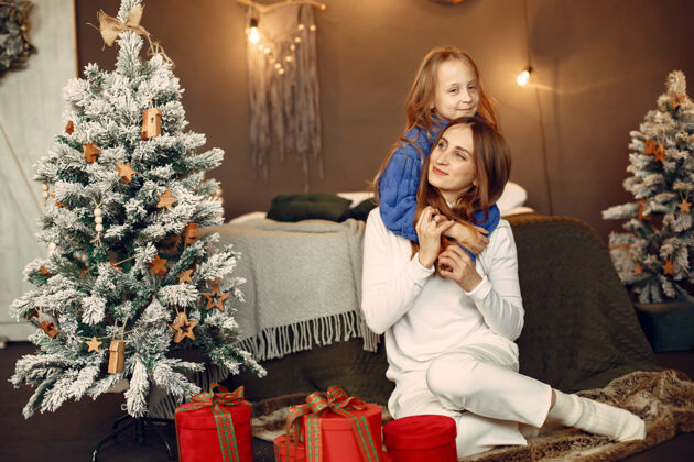 母亲人们在为圣诞节做准备母亲在和女儿玩耍一家人在节日的房间里休息孩子穿着蓝色毛衣传统孩子童年
