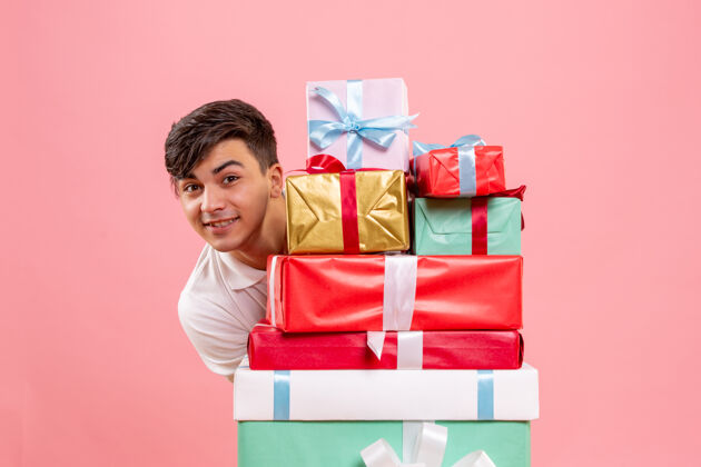 快乐粉红色墙上的圣诞礼物周围的年轻人的正面视图礼品盒快乐十二月