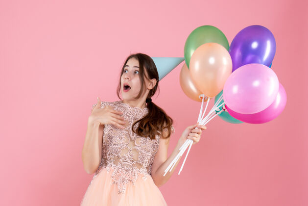 惊讶的聚会女孩惊讶的派对女孩 戴着派对帽 拿着气球 看着粉色的东西公主惊讶气球