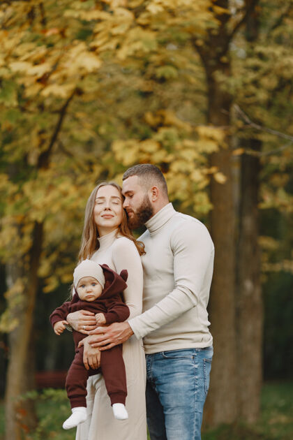 女人秋天公园里的一家人穿棕色毛衣的男人和父母在一起的可爱小女孩休闲头发男人