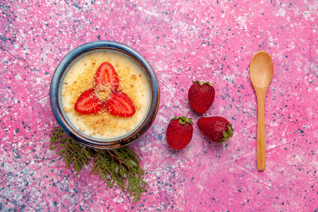 视图顶视图美味的奶油甜点与淡粉色背景上的红色草莓片甜点冰淇淋奶油色甜冰奶油甜点灯光
