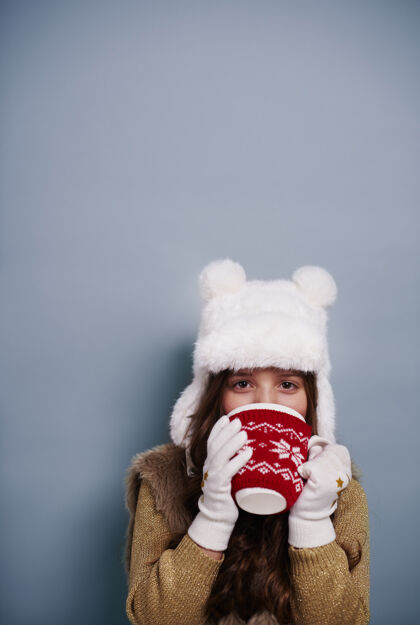 肖像在摄影棚里喝热巧克力的女孩圣诞节饮用帽子