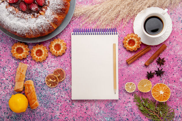 粉末俯瞰美味的草莓蛋糕糖粉蛋糕饼干笔记本和一杯茶的粉红色背景蛋糕甜甜的甜饼饼干馅饼饼干背景蛋糕