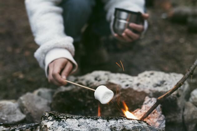 营地在营火中烧棉花糖的女人季节性和平放松