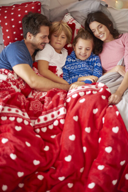 在一起一家人在床上的圣诞节懒惰放松睡衣庆祝