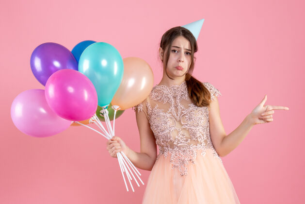 时尚戴着派对帽的悲伤派对女孩拿着粉色的气球公主悲伤连衣裙