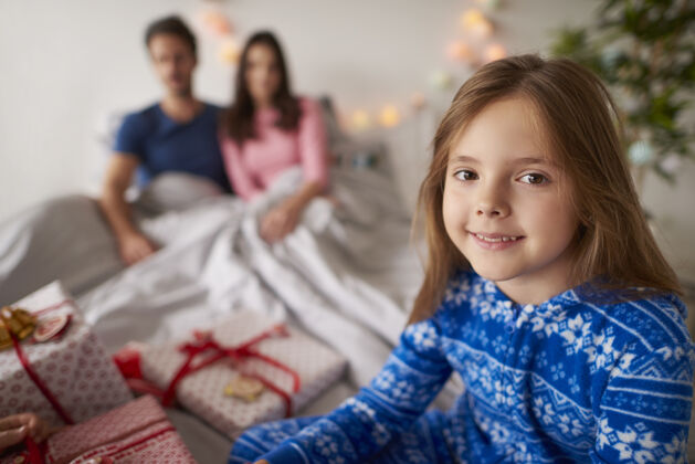 卧室小女孩等着打开圣诞礼物床坐着母亲