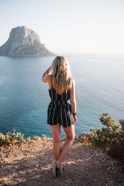 旅游白天站在美丽的海边悬崖上的迷人的年轻女性游客户外孤独