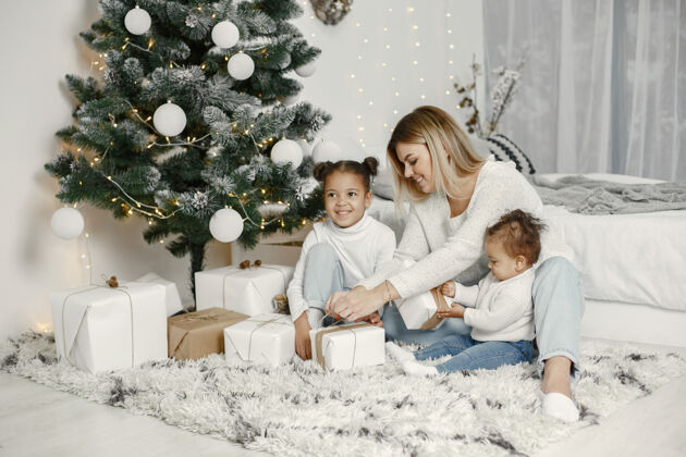 孩子人们在为圣诞节做准备母亲在和女儿们玩耍一家人在节日的房间里休息孩子穿着毛衣混合室内传统