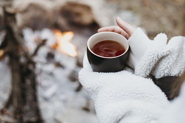 女孩在户外端着一杯热茶的女人温暖和平营地