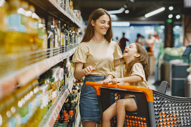 零售一家人在超市一个穿棕色t恤的女人人们选择产品母亲带着女儿消费主义产品人