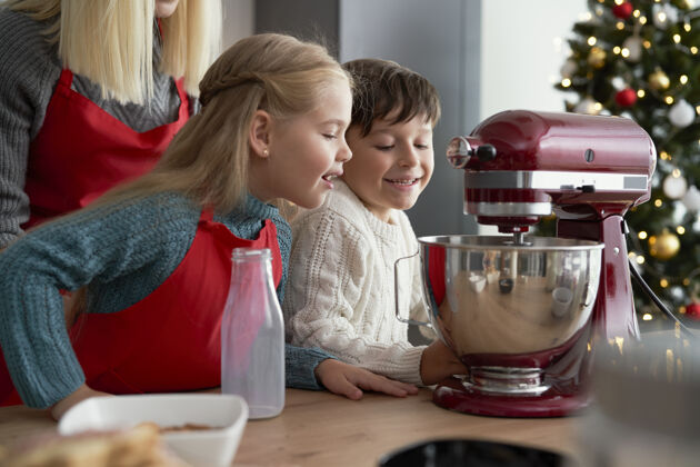 帮助好奇的孩子们看着电动搅拌机甜食自制碗