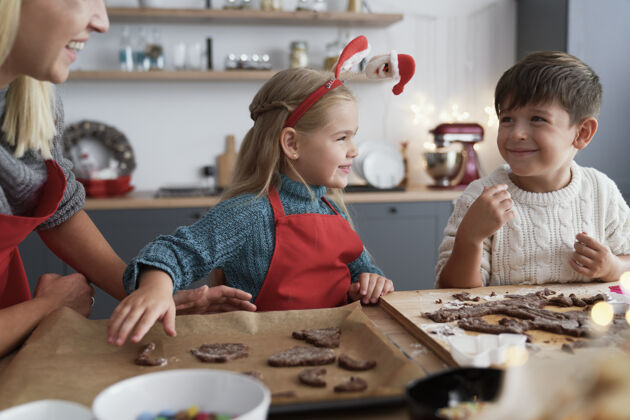 手工制作两个孩子和他们的妈妈切姜饼家庭厨房托盘节日