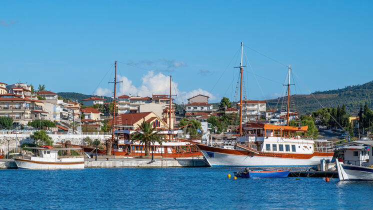 海岸建筑物坐落在山上 有多种绿化 码头与停泊在前景上的帆船 近地天体马尔马拉斯 希腊乡村岛蓝色