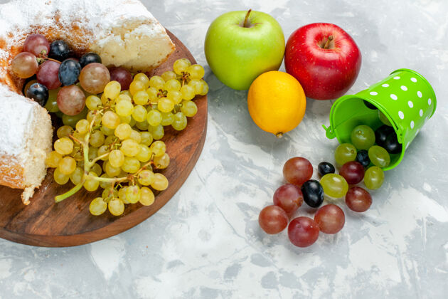 维生素半俯视图糖粉蛋糕加新鲜葡萄和苹果放在白色桌面上水果蛋糕饼干甜甜的糖烤粉末饼干桌子