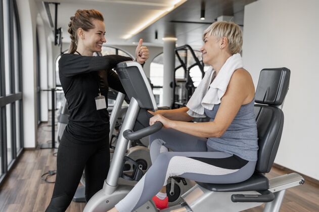 运动健身计划教练和客户使用自行车训练女人运动