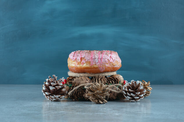 糖一个甜甜圈 一个花环和松果放在大理石表面美味松木上釉