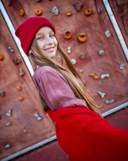 童年微笑的小女孩在攀岩墙旁摆姿势户外小垂直