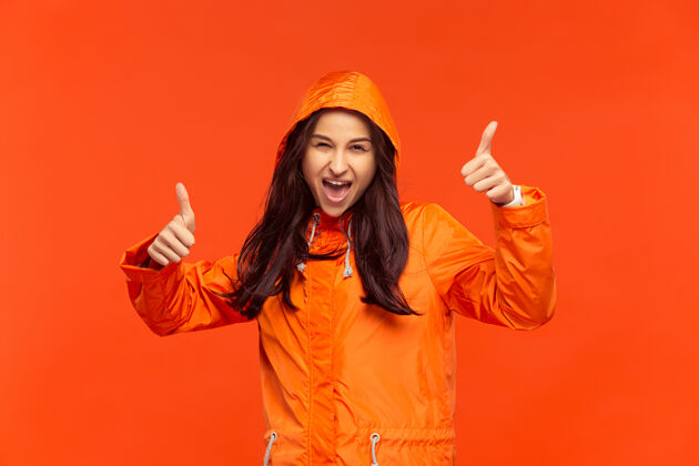 下雨一个快乐的微笑着的小女孩穿着秋天的橘色夹克在摄影棚里摆姿势保护安全惊喜