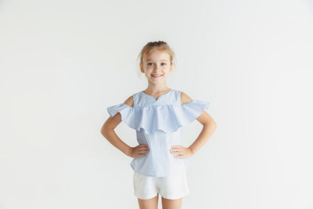 可爱时尚的微笑小女孩穿着休闲装在白色的工作室里站立成功服装