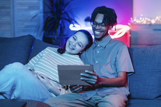 设备笑脸夫妇在沙发上使用平板电脑科技年轻现代