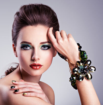 假漂亮的女人脸 手上有时尚的绿色化妆品和珠宝指甲豪华优雅