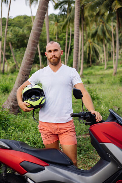 夏天在热带丛林地带骑着红色摩托车的壮汉控制保护运动