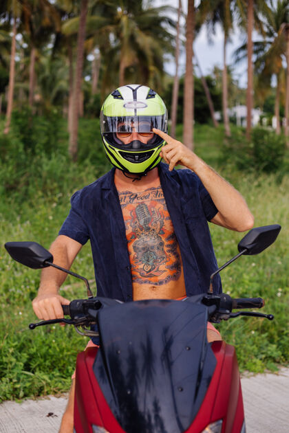 人在热带丛林的田野上纹着红色摩托车的壮汉运动自由交通