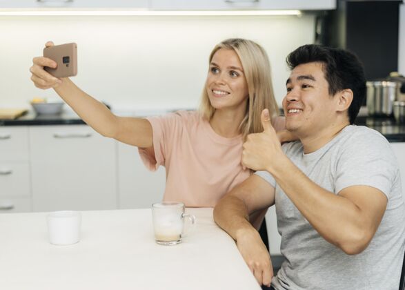 冠状病毒大流行期间笑脸情侣在家用智能手机自拍流行病马克杯Ncov