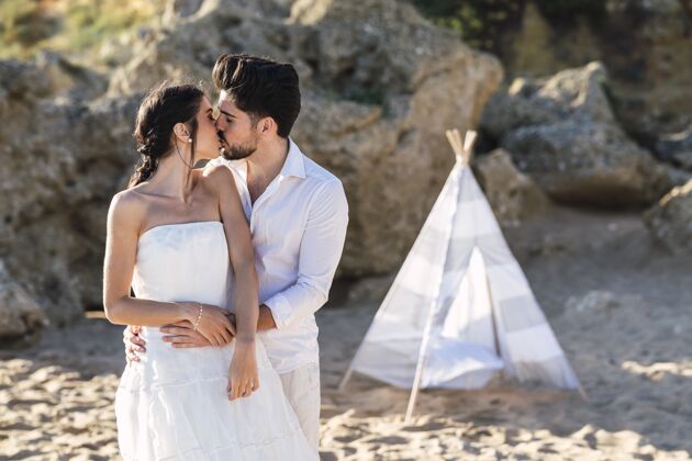 亲吻新娘和新郎在海滩上互相亲吻拥抱庆典妻子