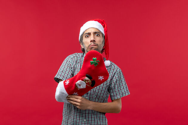 男人红墙上穿着圣诞袜的年轻人的正视图快乐圣诞肖像
