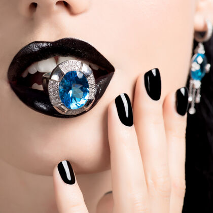指甲一个女人的嘴唇和指甲被涂成亮黑色的宏观照片嘴唇化妆品配件