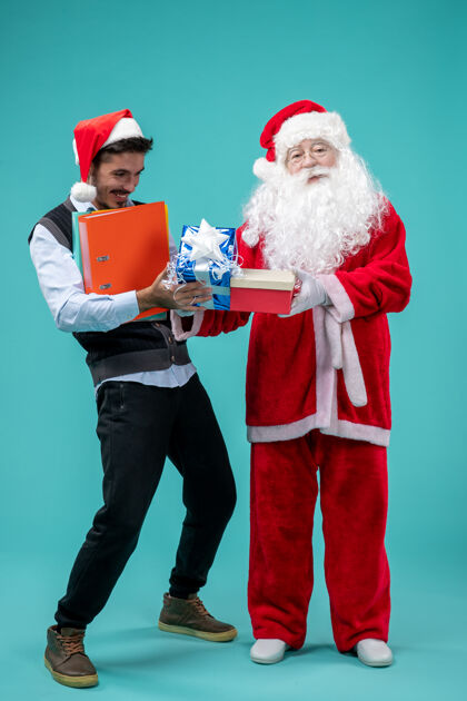 礼物圣诞老人与年轻人和礼物在蓝色墙上的正面视图节日庆祝假期